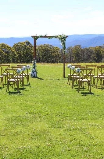 Aisle Florals displayed on chairs set in a country field for wedding guests